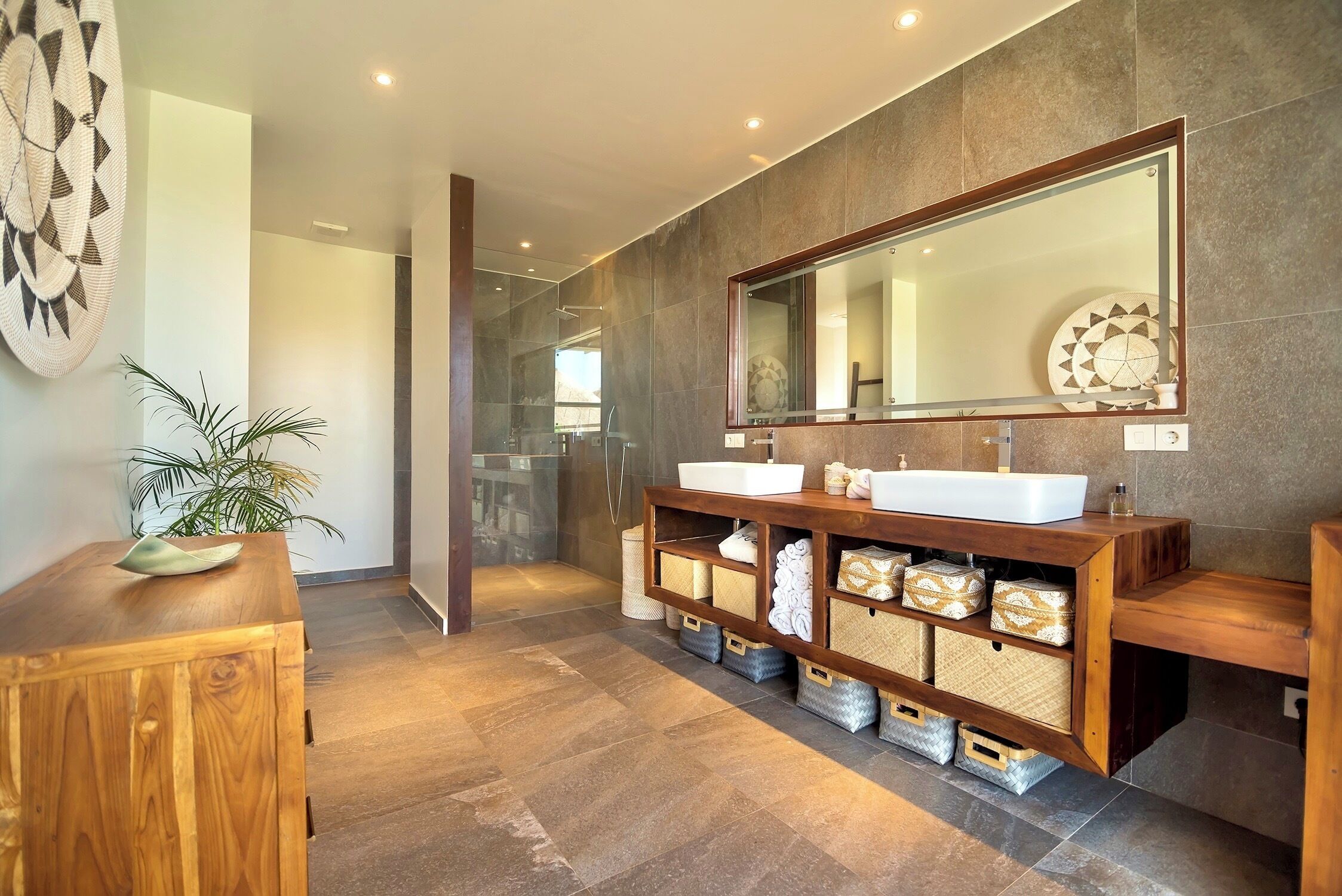 Un baño moderno con un espejo grande, tocador de madera y cabina de ducha de vidrio.