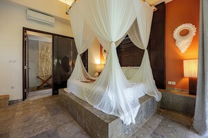 A room with a four-poster canopy bed, a statue, and a decorative wall piece.