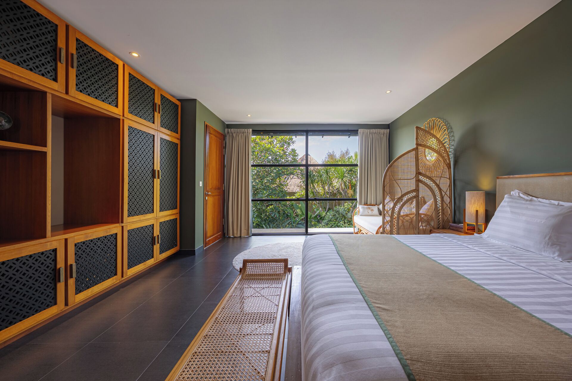Un dormitorio con una cama grande, un armario de madera y vistas al exterior a zonas verdes.