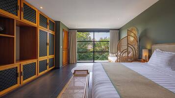 Un dormitorio con una cama grande, un armario de madera y vistas al exterior a zonas verdes.