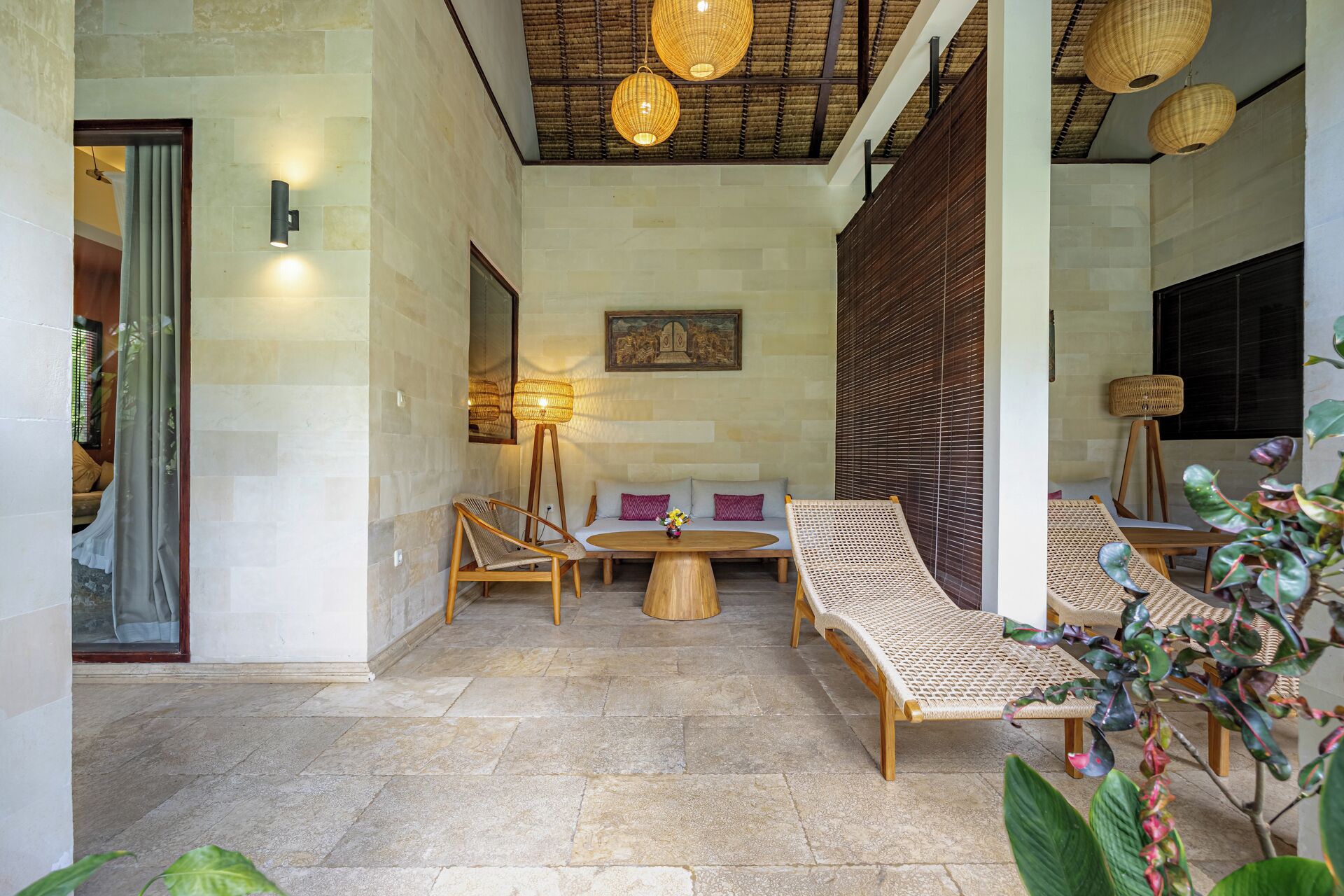 A spacious outdoor seating area with wicker furniture, a round table, and a ceiling with woven light fixtures.