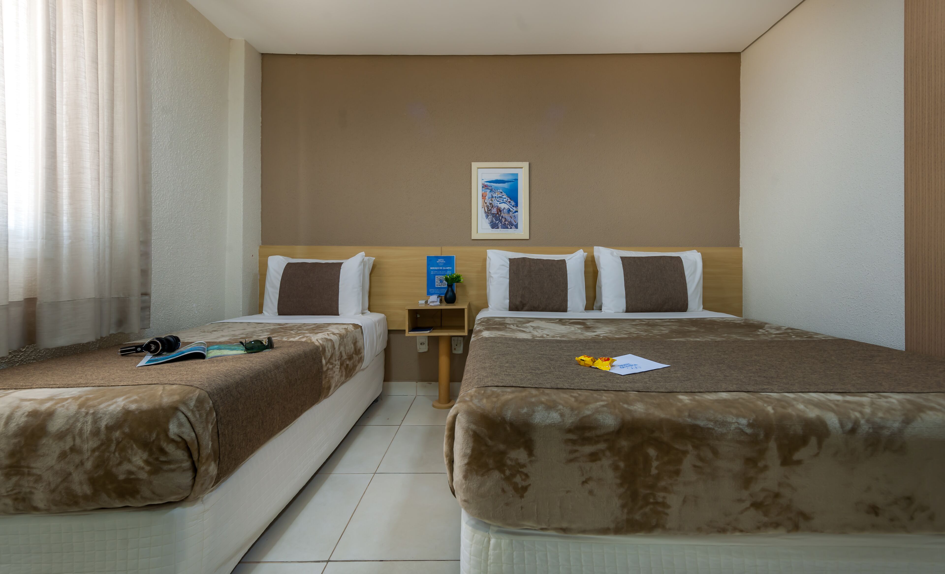 A hotel room with two beds, a small table, and a picture on the wall.