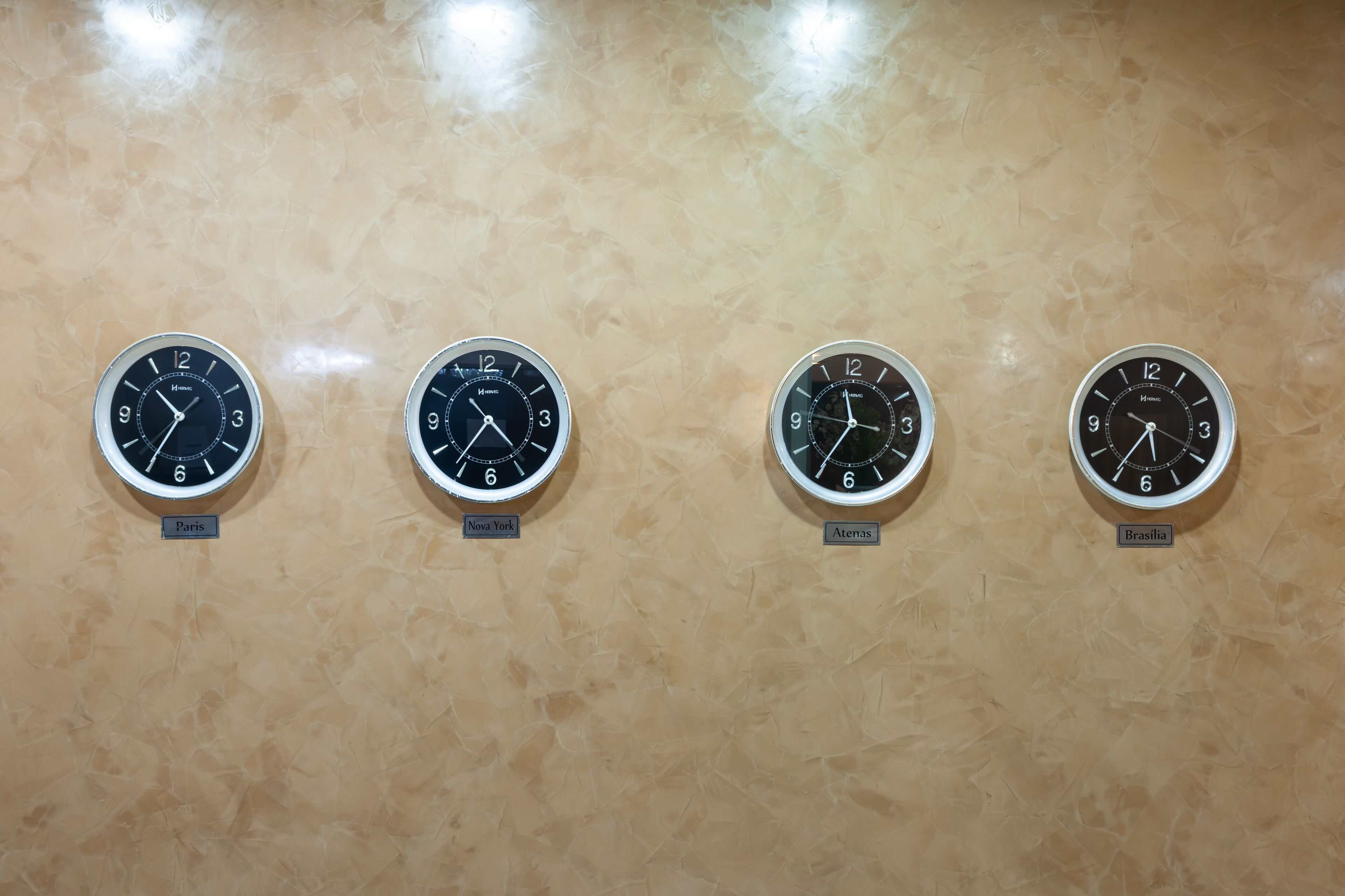 Four wall clocks labeled with city names: Paris, Nova York, Athens, and Brasilia.