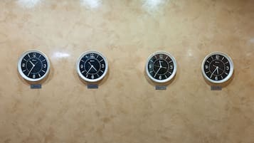 Four wall clocks labeled with city names: Paris, Nova York, Athens, and Brasilia.