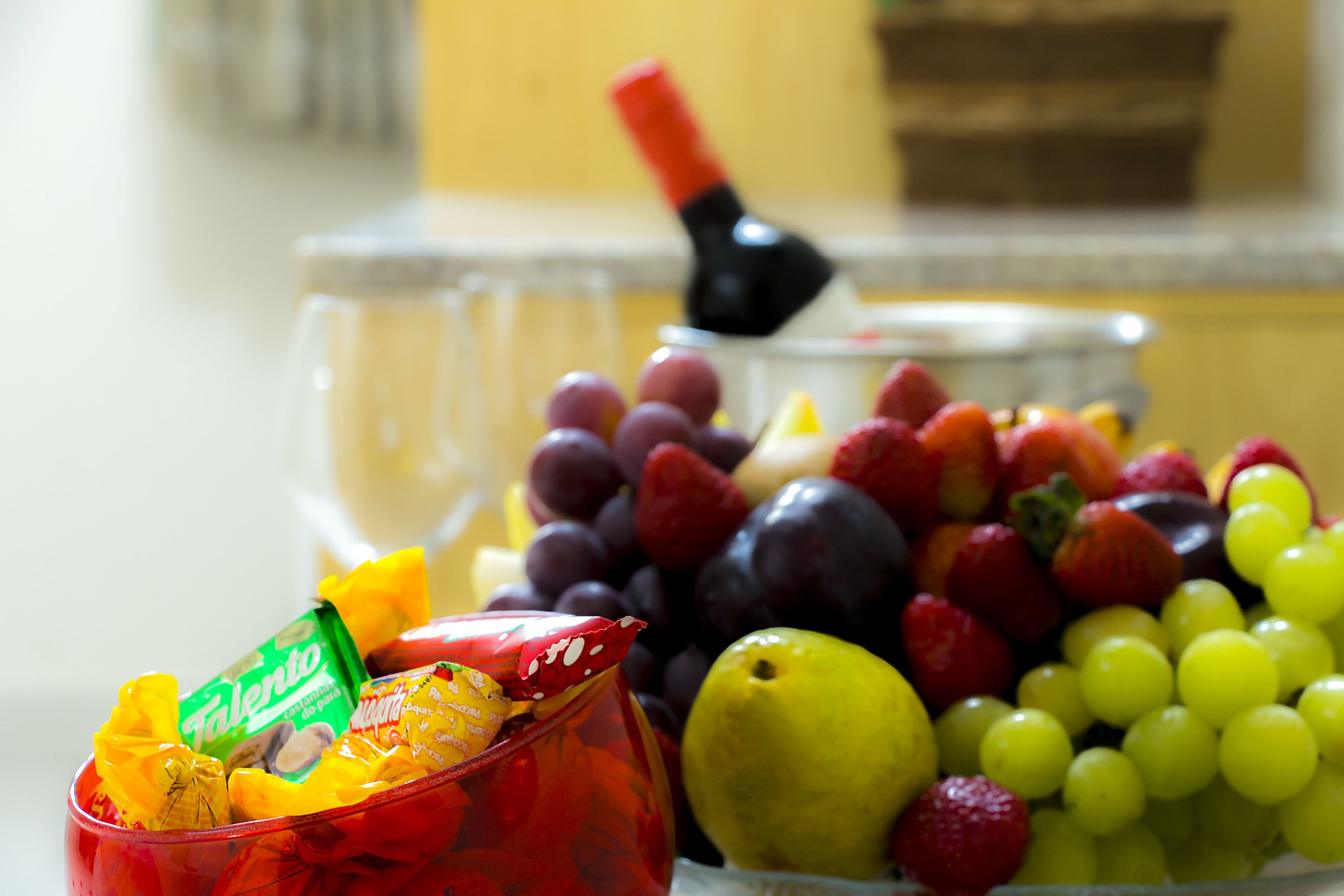 Uma tigela com frutas variadas e um recipiente vermelho com balas.