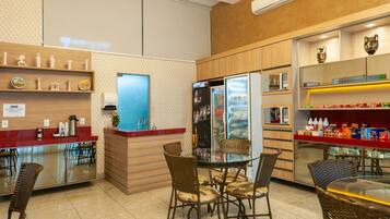Un restaurante con mostrador, zona de mesas y un refrigerador.