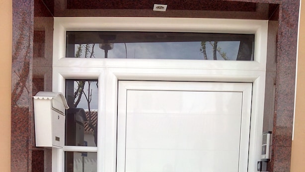 A white door with a handle, a glass panel, and a small light fixture above it.