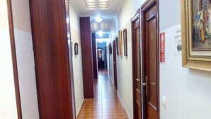 A hallway with wooden doors, tiled flooring, and a ceiling with recessed lighting.