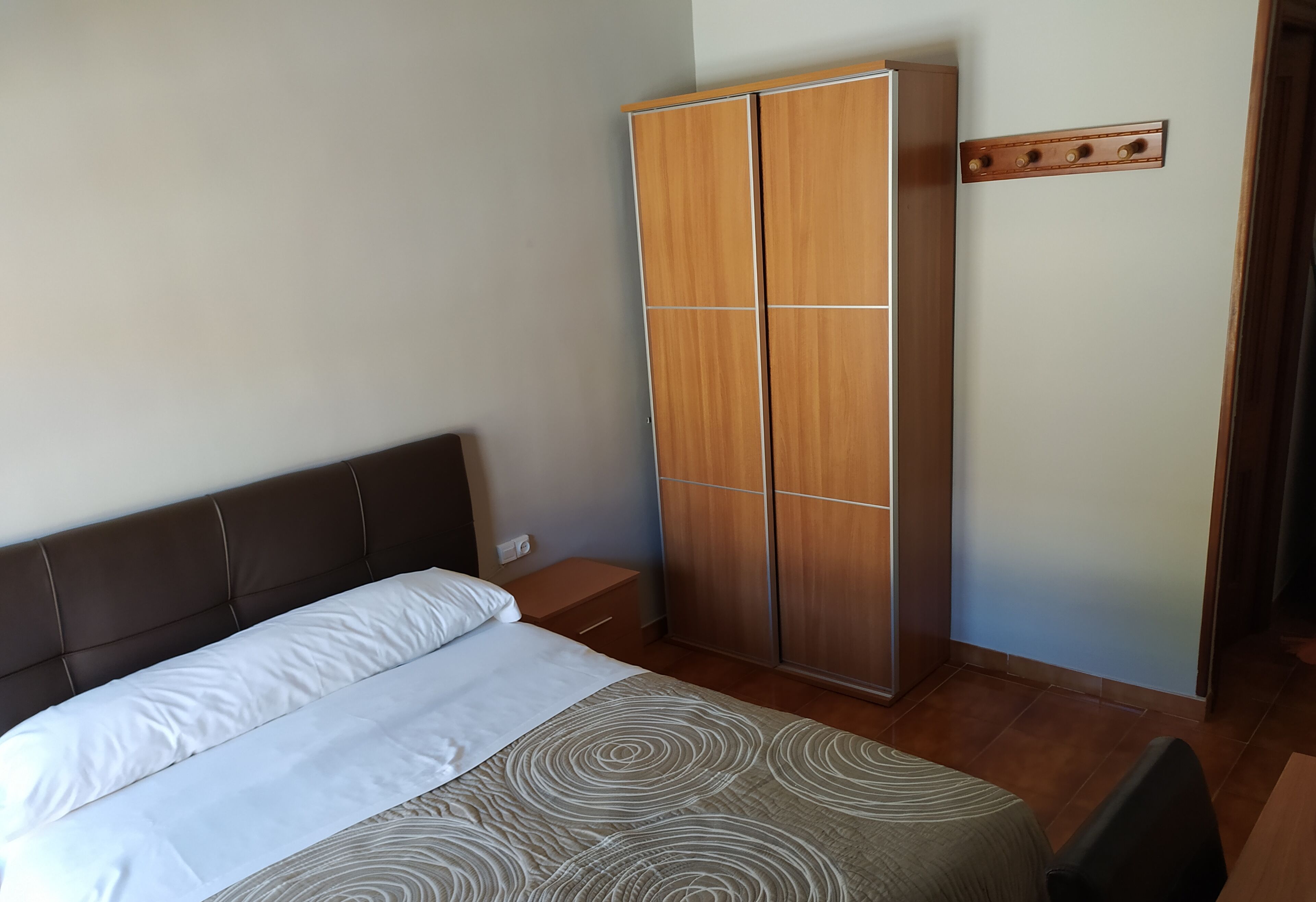 A bedroom with a bed, a wardrobe, and a nightstand.