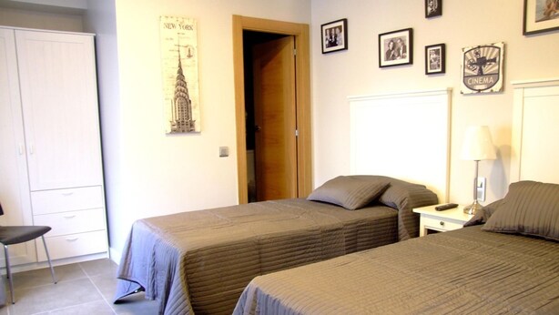 A hotel room with two beds, a chair, a desk, and a wardrobe. - Hostal Vintage Santander (Santander)