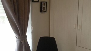 A room with a single chair, a wardrobe, and two framed pictures on the wall. - Hostal Vintage Santander (Santander)