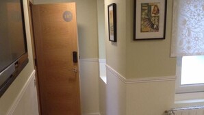 A narrow hallway with a wooden door marked "107", a radiator, and a framed picture on the wall. - Hostal Vintage Santander (Santander)