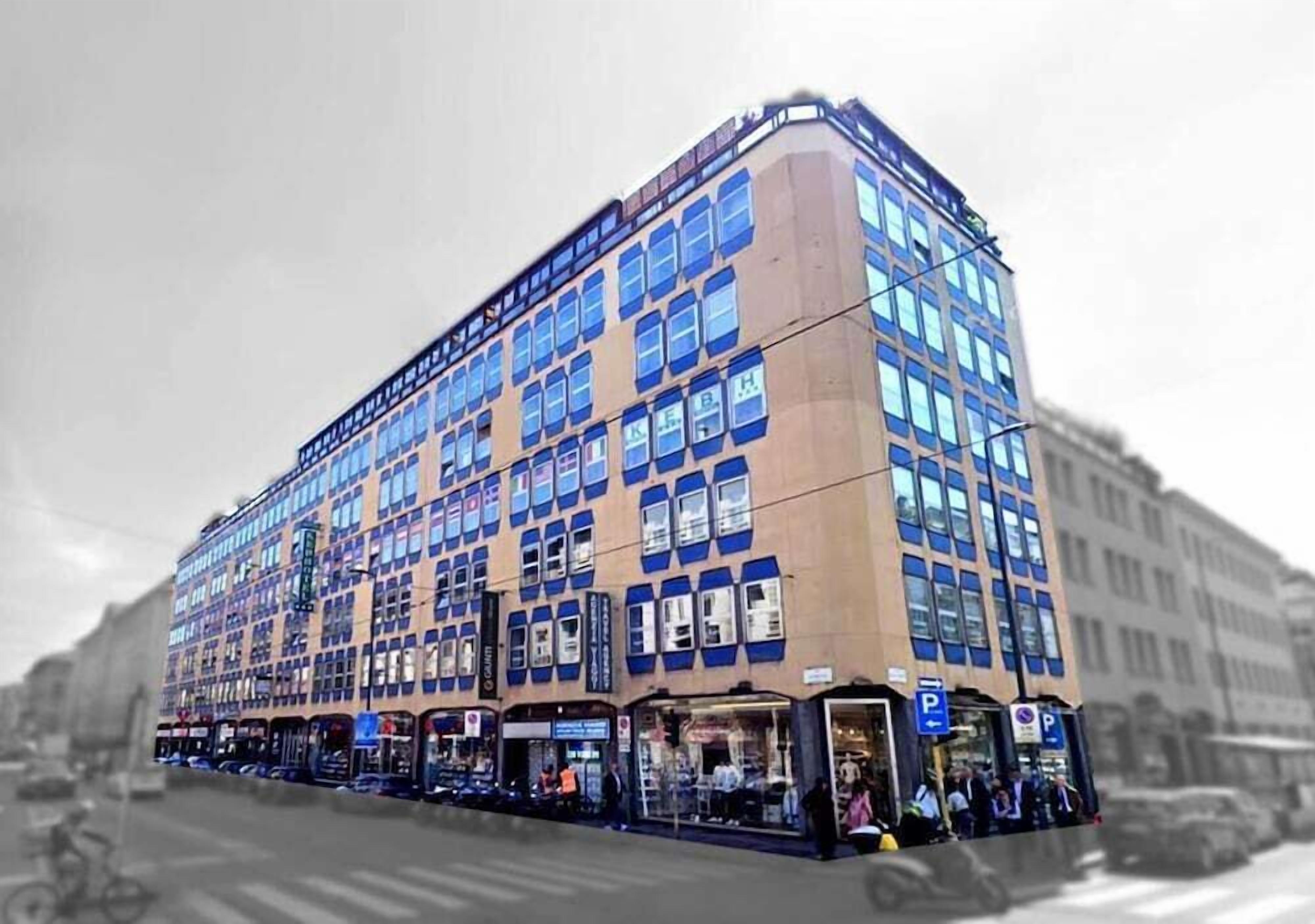 A multi-story building with a corner entrance, large windows, and storefronts on the ground level.