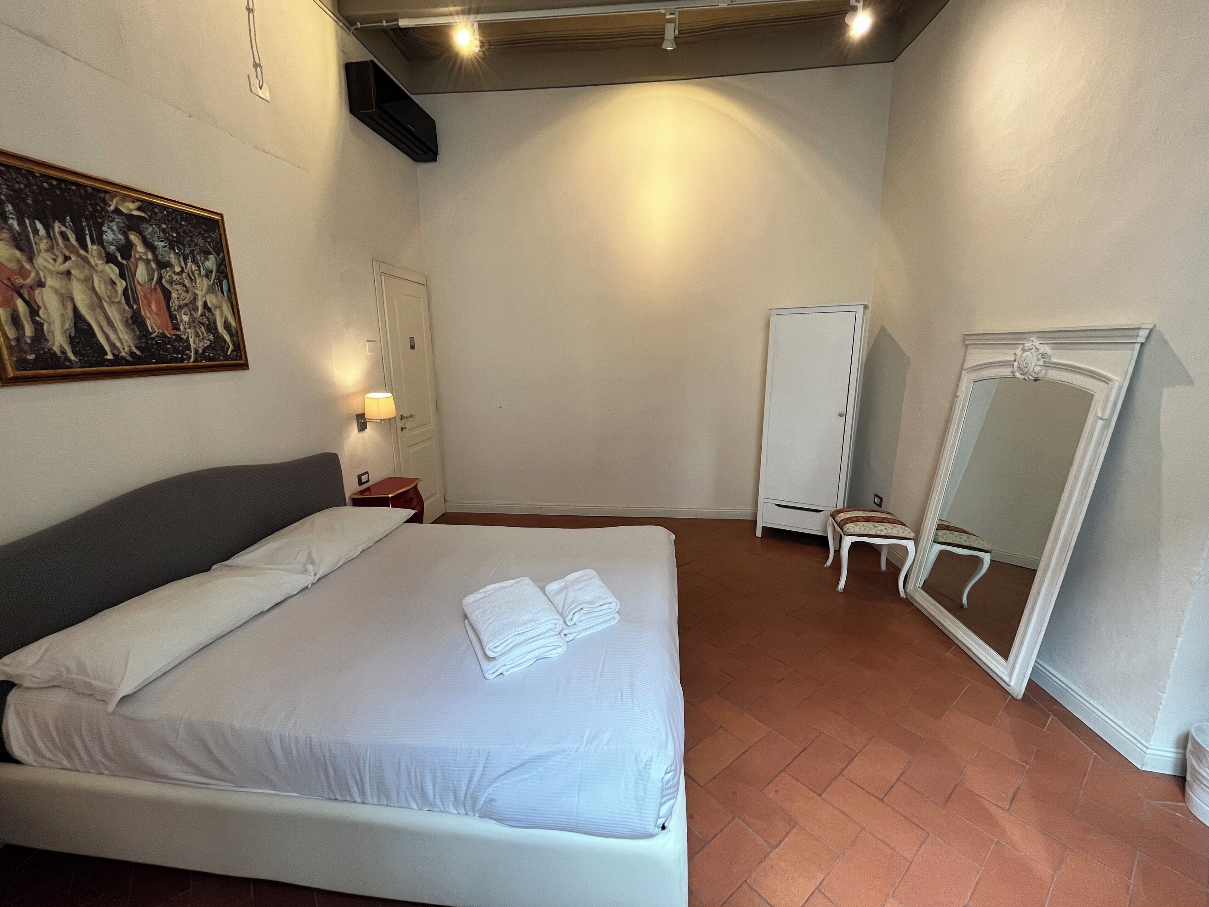 Un dormitorio con una cama, un cuadro, un armario y un espejo.