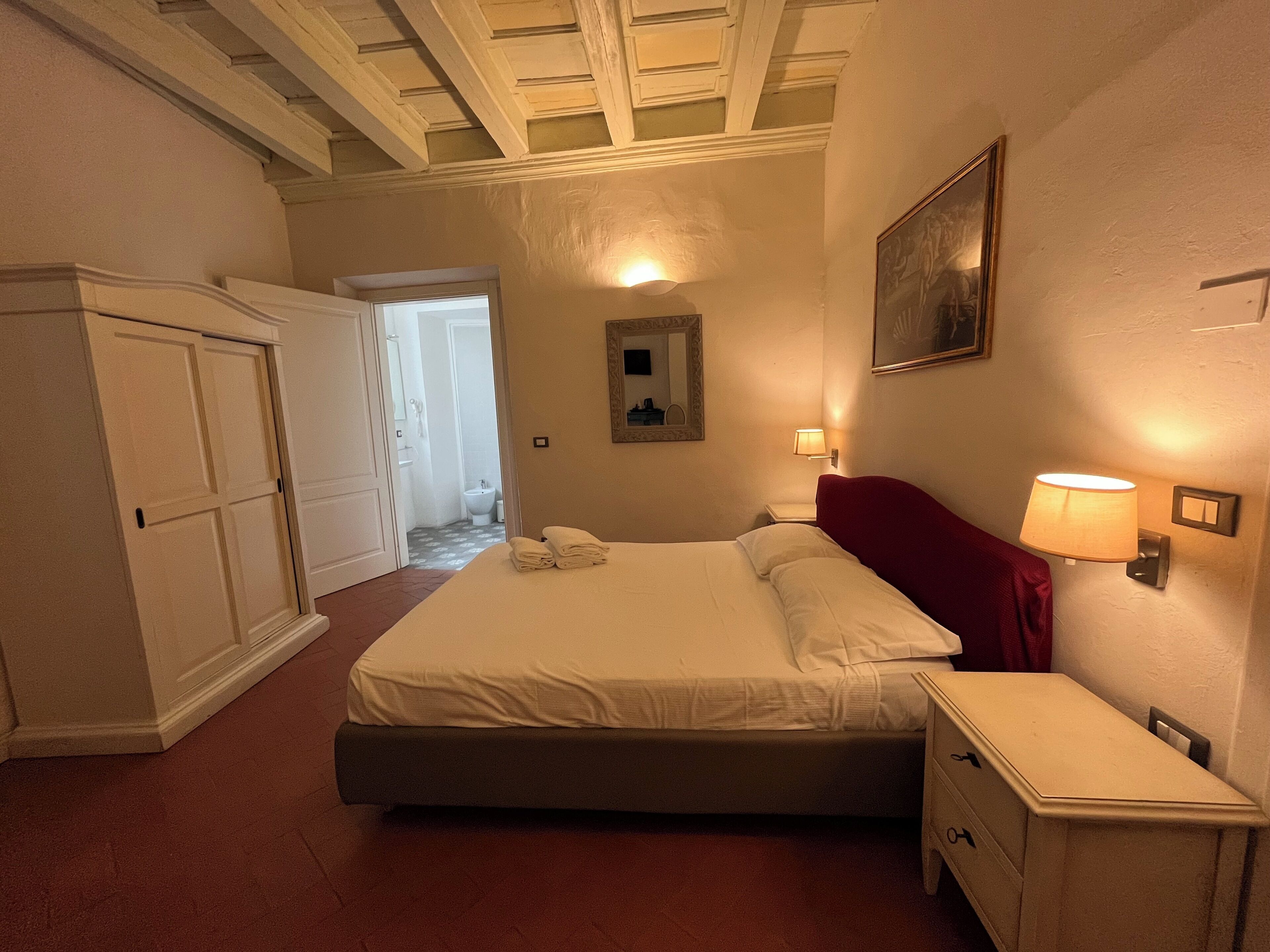 Une chambre à coucher comprenant un lit, des tables de chevet, un miroir et une porte donnant sur une salle de bain.