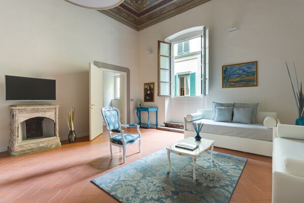Una sala de estar con chimenea, un sofá, un sillón y un televisor.