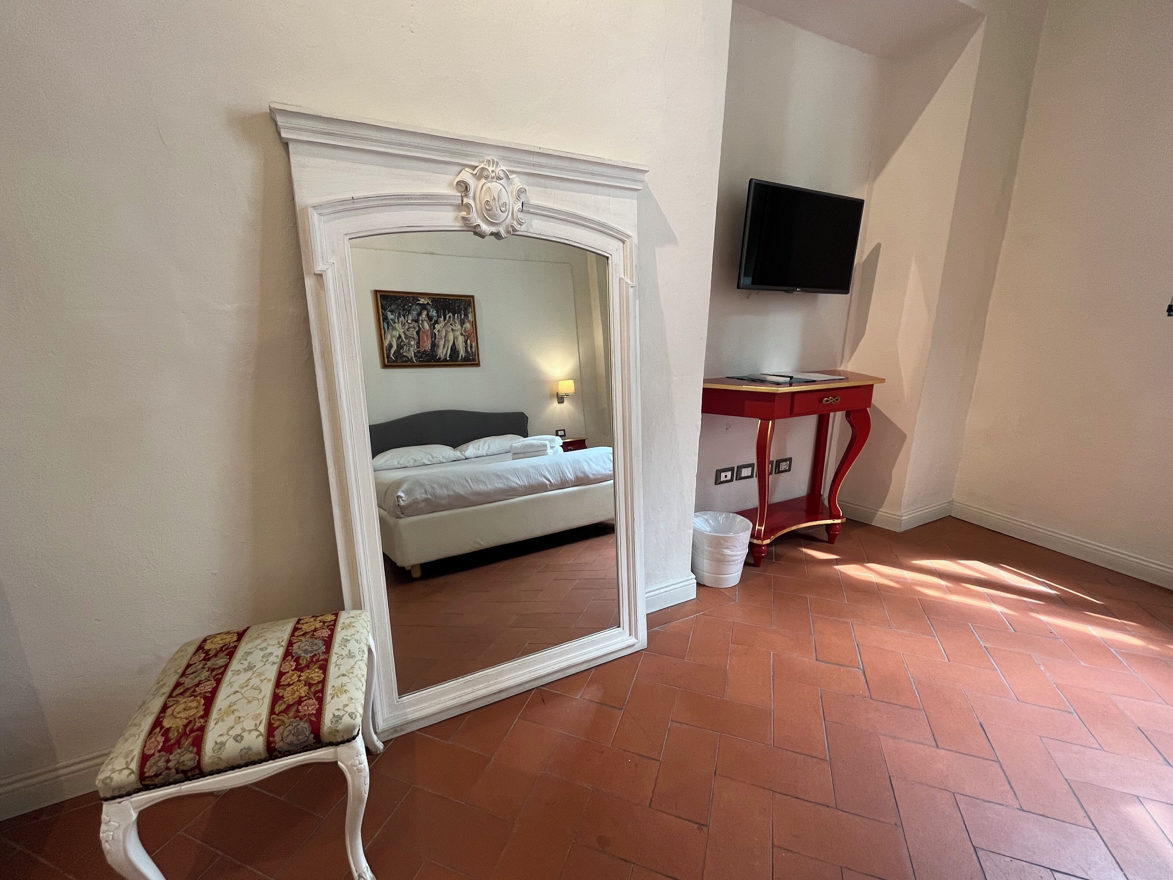 Ein Schlafzimmer mit einem großen Spiegel, einem Bett, einem kleinen Tisch und einem Fernseher.