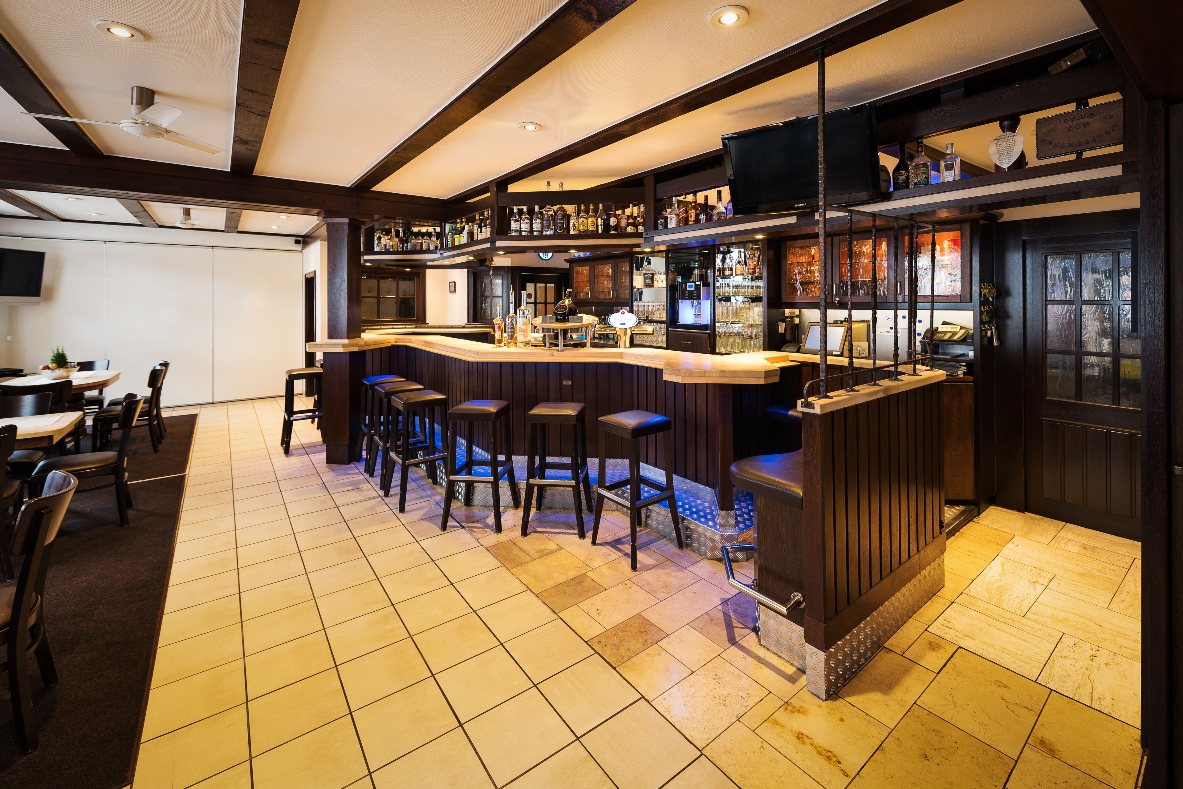A bar area with a counter, stools, and a television screen.