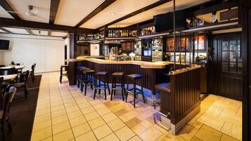 A bar area with a counter, stools, and a television screen.