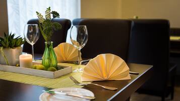 Una mesa de comedor dispuesta con una vela, un florero con flores y dos copas de vino.