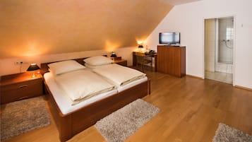 A bedroom with a wooden bed, bedside tables, a desk, a television, and a shower area.