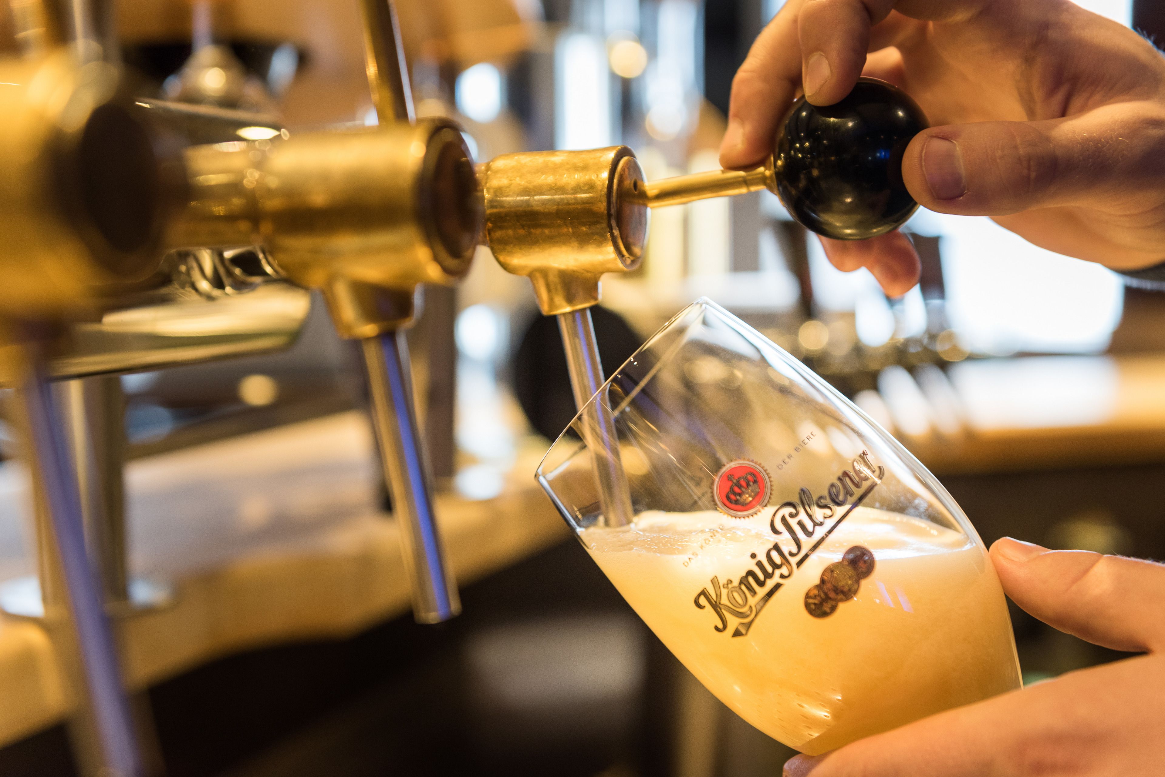A hand pouring beer into a glass labeled "Königsberg."