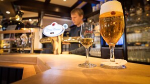 A bar setting with a glass of beer and a bottle of SASSER beer on the counter. - Hotel Nagel (Sudlohn)
