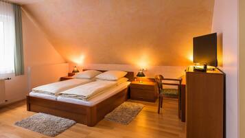 Un dormitorio con cama, mesitas de noche, escritorio y televisor.