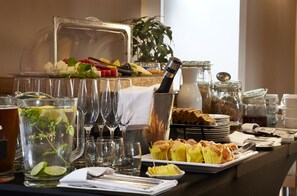 A buffet setup with various food items, a pitcher of iced tea, and multiple glasses.