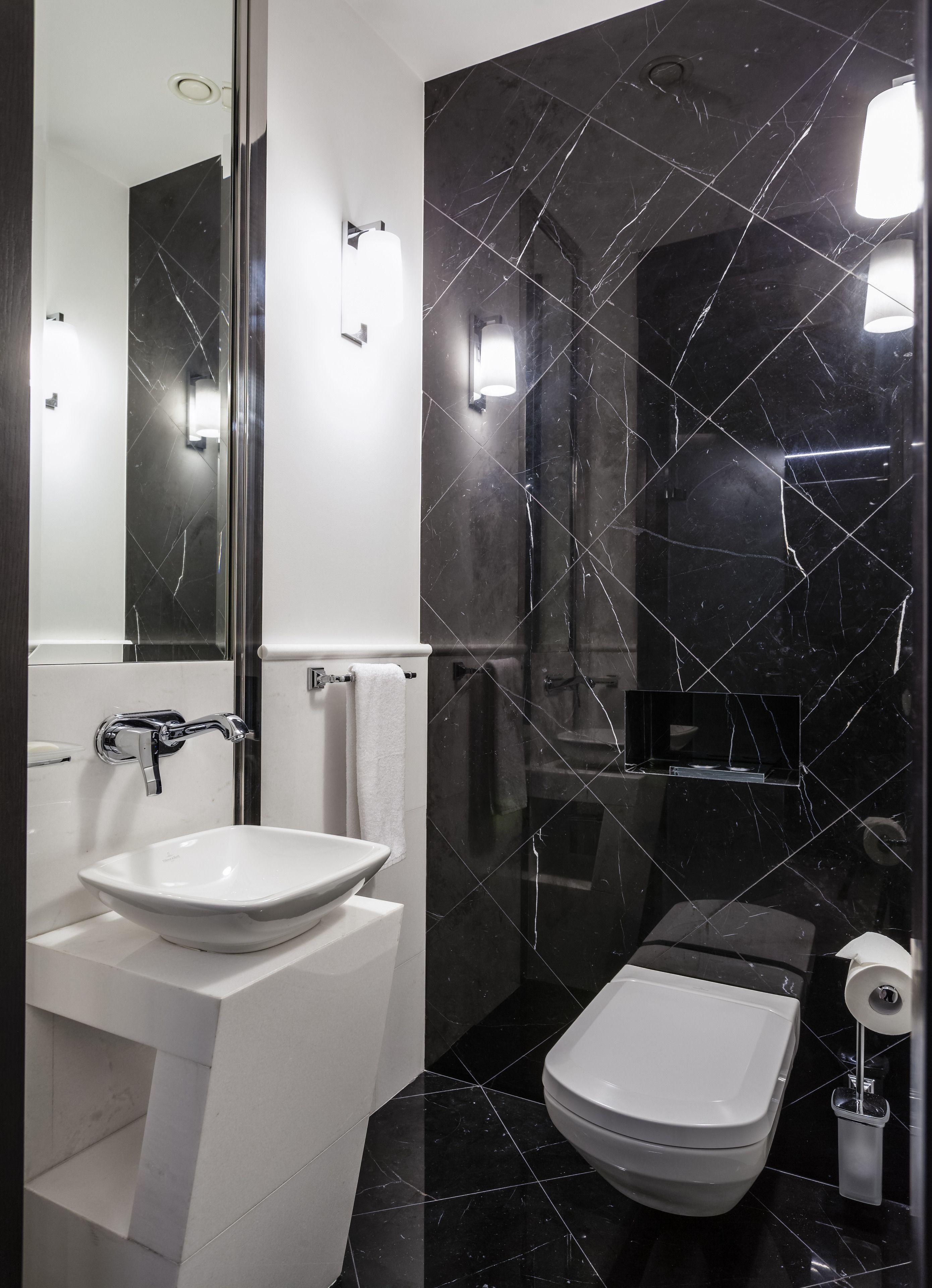 Un baño moderno con lavamanos blanco, inodoro y zona de ducha.