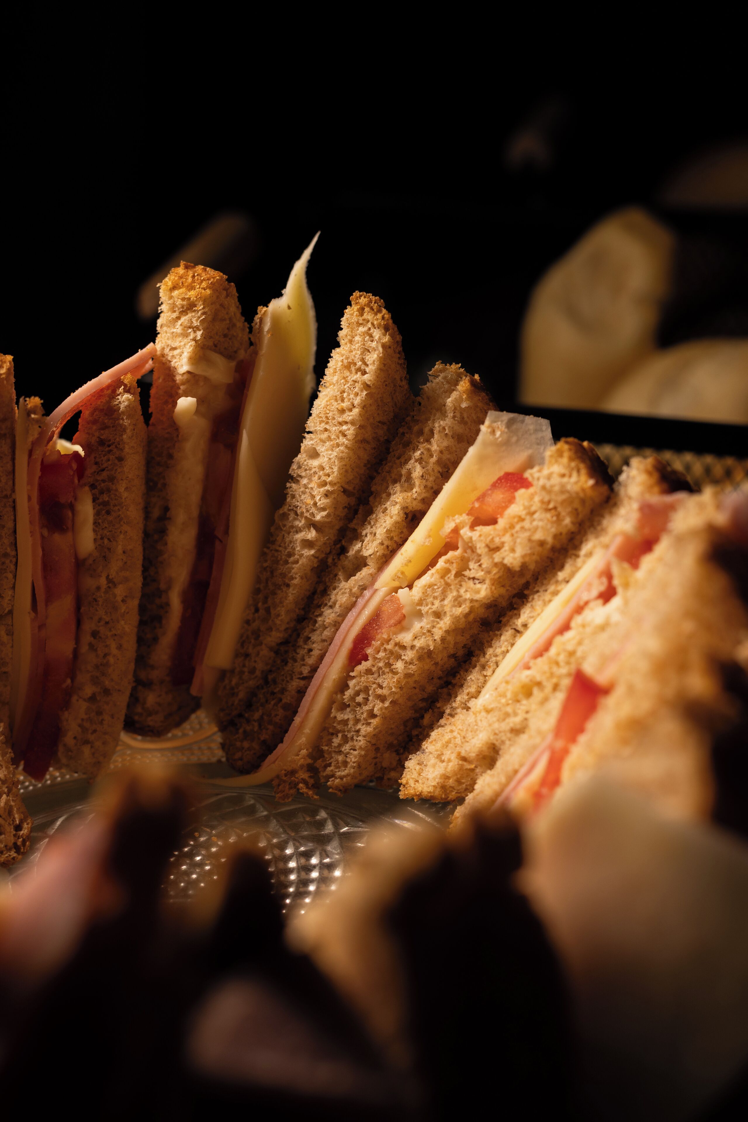 A close-up of a sandwich with visible layers of bread, cheese, and ham.