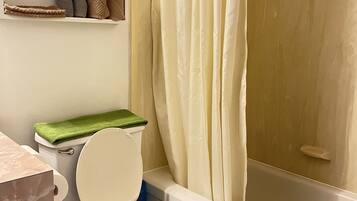 Une salle de bain équipée de toilettes, d’une baignoire et d’un rideau de douche.