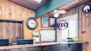 Un mostrador de recepción de madera con un reloj, un letrero de neón y un calendario.