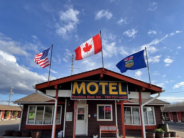 A motel with a signboard displaying the name and contact number.
