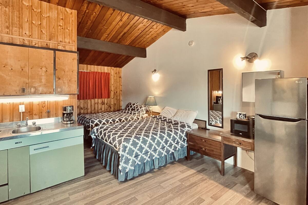 A modern bedroom with a bed, bedside table, and a built-in L-shaped desk.