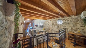 A rustic interior with exposed wooden beams, stone walls, a kitchen area, and a dining space with a view of the kitchen. - Villa Split Heritage Hotel (Split)