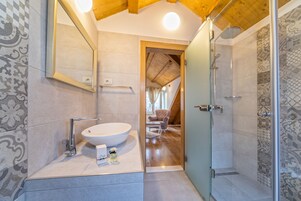 A modern bathroom with a large sink, a mirror, and a shower area.