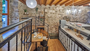 A rustic stone interior with a wooden staircase, a dining area with a table set for two, and a breakfast bar with various food items. - Villa Split Heritage Hotel (Split)