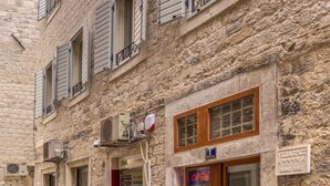 A stone building with multiple windows, some with shutters, and a storefront with a sign that reads "CAMBIO VALUTE". - Villa Split Heritage Hotel (Split)