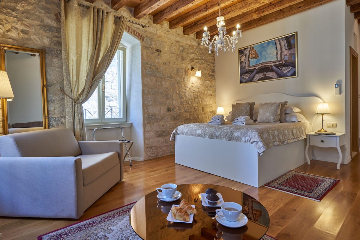 Une chambre confortable avec un lit, une table de chevet et une table basse sur laquelle sont disposées des pâtisseries et des tasses.