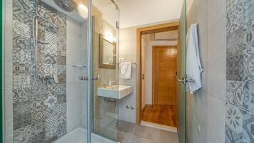 Une salle de bain moderne avec une douche à parois de verre, une porte en bois et des carreaux décorés.