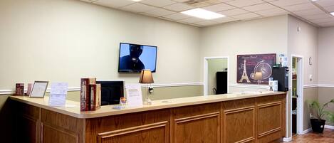 A reception desk with a television, framed certificates, and a poster of the Eiffel Tower.