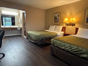A hotel room with two beds, a desk, a chair, a mirror, and a painting on the wall. - Paris Inn and Suites (Paris)