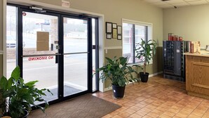 A reception area with a tiled floor, potted plants, a reception desk, and framed certificates on the wall.