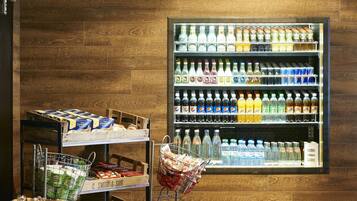 A grocery store interior with wooden flooring, a refrigerated beverage display, and various packaged goods on shelves.