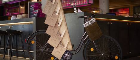 A bicycle with a wooden structure attached to its frame, positioned in a modern indoor setting with bar stools and a counter.