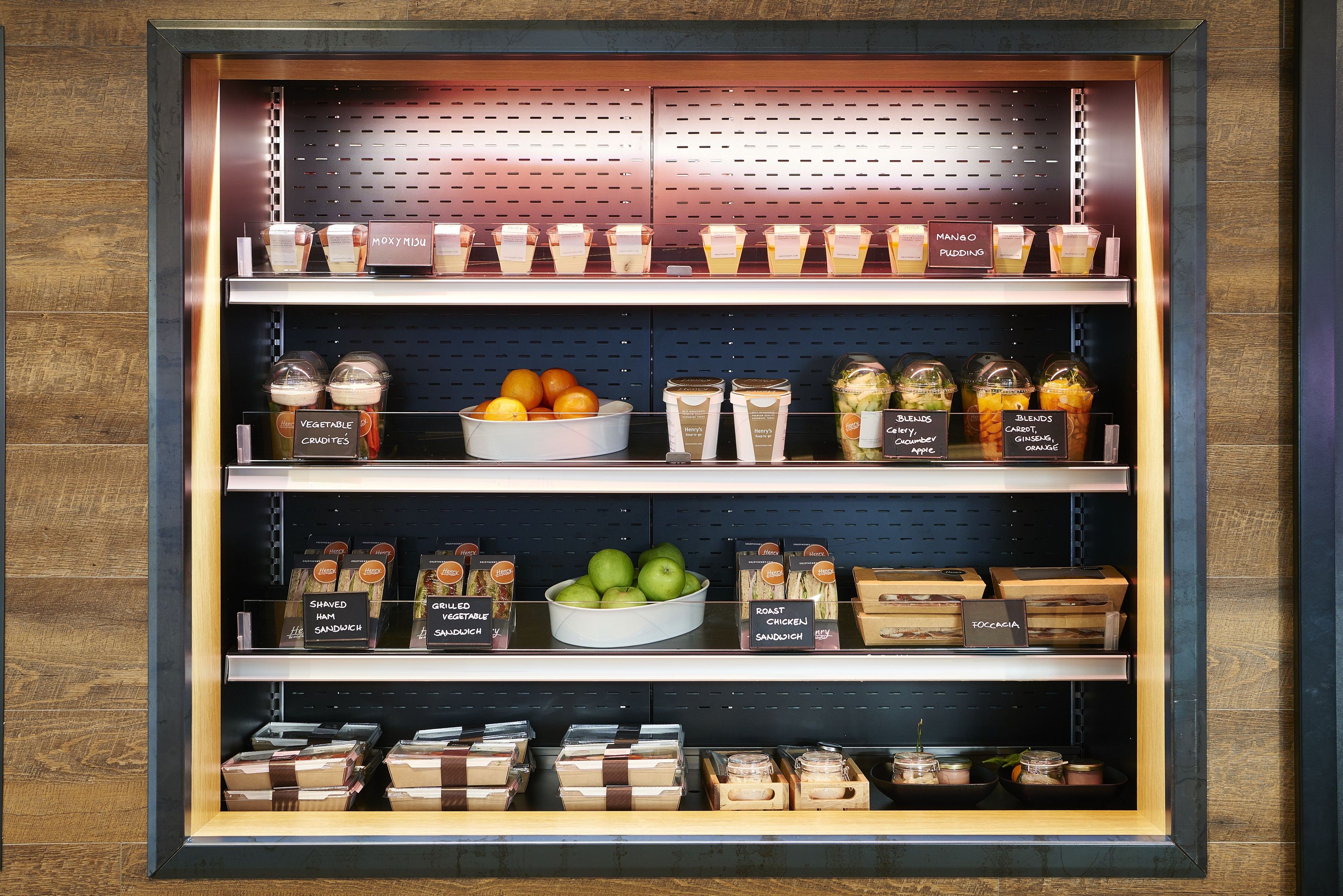 A display case with various food items including fruits, vegetables, and packaged goods.
