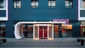 Un edificio moderno con una entrada curva distintiva y un letrero de neón.