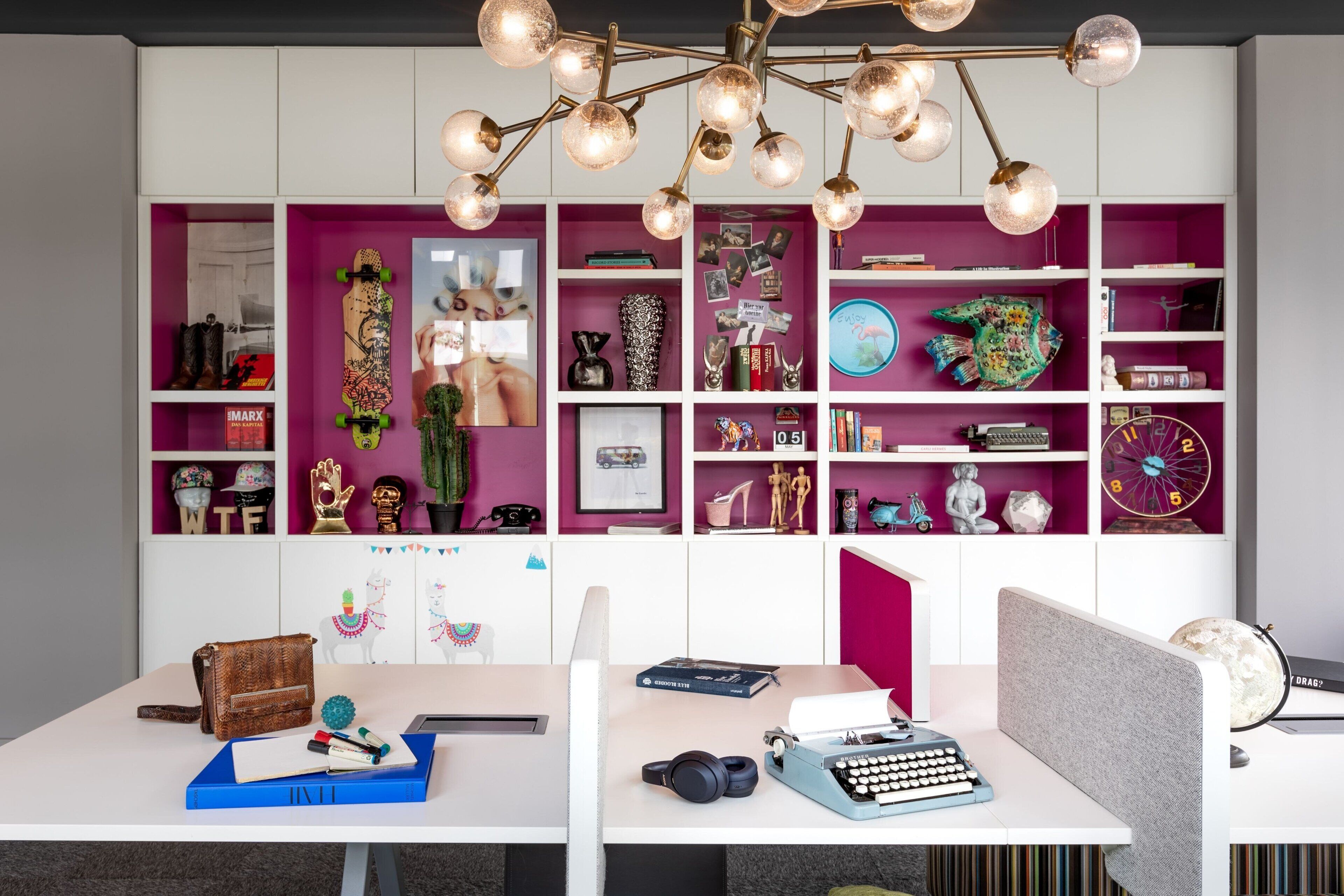 A modern workspace with a desk, chair, and a large bookshelf filled with various items.
