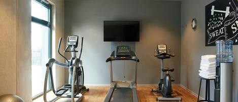 Un gimnasio con cintas de correr, elípticas y una bicicleta estática.